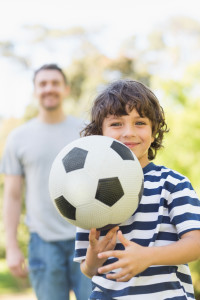 Portrait of a father and son playing football in the park